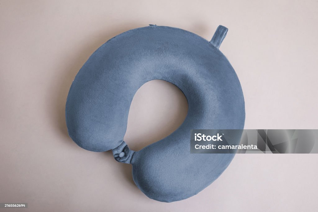 blue travel neck pillow made of fluffy fabric on a beige background